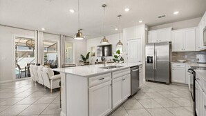 A modern kitchen with white cabinetry, stainless steel appliances, and pendant lighting. - Last Minute Disney Getaway! Private Pool & Comfortable Bedrooms. Book Now! #147409 (Orlando)