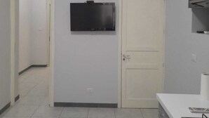Una cucina con una TV a parete, una porta bianca e un fornello.