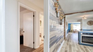 A hallway with a wooden floor and a wall with a vertical wood panel design. - The Nest with Firepit & Backyard Swings (Klamath Falls)
