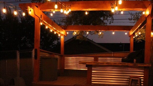 An outdoor patio area with a fire pit, wooden steps, and string lights. - The Nest with Firepit & Backyard Swings (Klamath Falls)