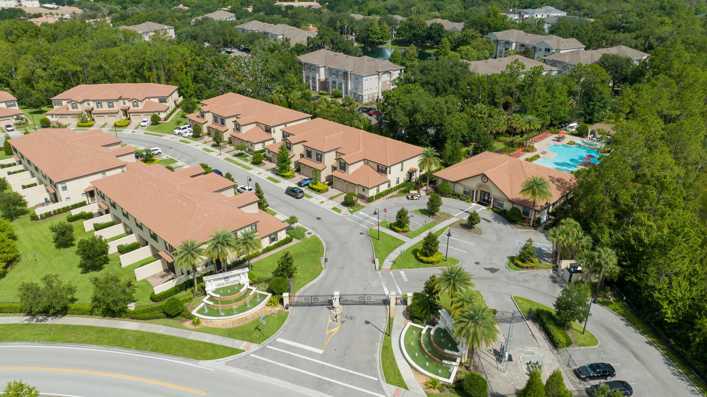 A residential area with multiple two-story houses, a gated entrance, and a swimming pool.
