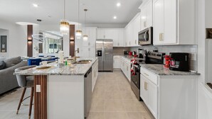 Une cuisine moderne avec des meubles blancs, des appareils en acier inoxydable et un îlot central.