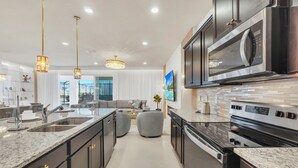 A modern kitchen with granite countertops, stainless steel appliances, and pendant lighting. - Last Minute Disney Getaway! Private Pool, Game Room & Themed Bedrooms. Book Now! #147905 (Orlando)