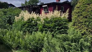 En röd byggnad omgiven av tät vegetation.