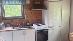 Ett kompakt kök med träväggar, ett fönster med utsikt, ett kylskåp från Bosch och en spis.