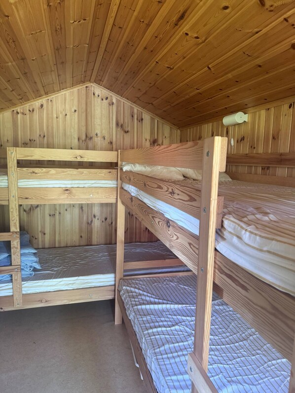 A wooden bunk bed room with a sloped ceiling and wooden walls.