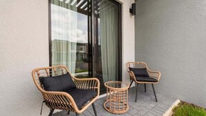 A balcony with two wicker chairs and a small round table.
