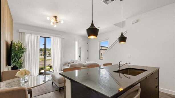 A modern kitchen with a central island, pendant lighting, and a view to the outdoors.