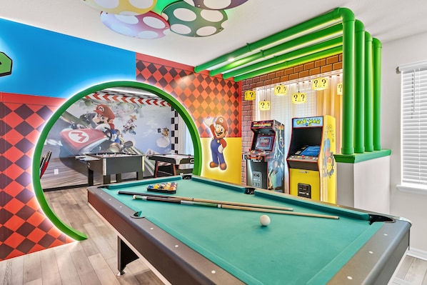 Une table de billard recouverte d’un drap vert, un queue de billard et une bille blanche.