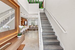 A modern interior with a staircase, a dining area, and a kitchen.