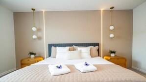 Un letto rifatto con copriletto trapuntato, due comodini con lampade e una testiera blu.