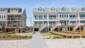 A beachfront hotel with multiple balconies, wooden decks, and a sandy walkway leading to the entrance. - Las Brisas (Port St. Joe)