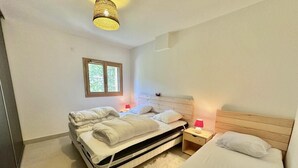 A bedroom with two beds, a window, and a nightstand with a lamp.