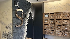 A reception area with a stone wall, a large 'LE' sign, and a wooden storage unit with multiple compartments.