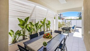 Une terrasse avec une table dressée pour le repas, entourée de plantes en pot et d’un baby-foot.