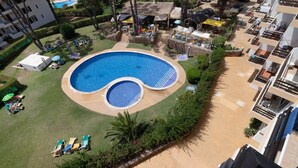 Una grande piscina circondata da lettini e ombrelloni, con un edificio sullo sfondo.