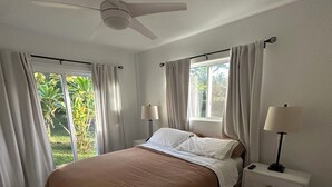 A bedroom with a bed, nightstands, a ceiling fan, and a window with curtains. - Traveling Nurse Haven - 3BR, Furnished, WiFi, AC (Hilo)