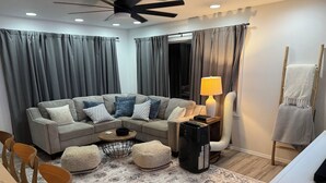 A modern living room with a sectional sofa, a coffee table, a lamp, and a heater. - Traveling Nurse Haven - 3BR, Furnished, WiFi, AC (Hilo)