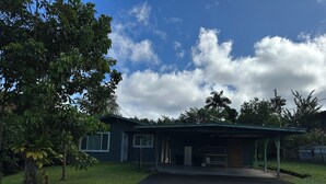 A single-story house with a covered porch, a garage, and a driveway leading to the front door. - Traveling Nurse Haven - 3BR, Furnished, WiFi, AC (Hilo)