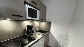 Una cocina compacta con estufa, microondas, fregadero y lavavajillas.