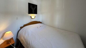Una cama individual con cabecera de madera, una lámpara de pared y una decoración de cabeza de venado en marco.