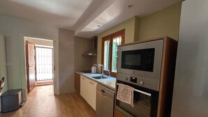 Una cocina con microondas, horno y lavamanos. Se aprecia una ventana con vistas al exterior.