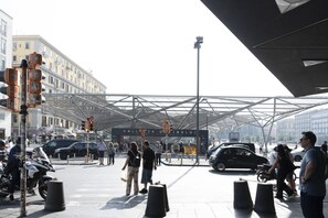 A busy urban intersection with traffic lights, pedestrians, and a modern glass structure overhead. - Casa Cidis by Wonderful Italy (Naples)