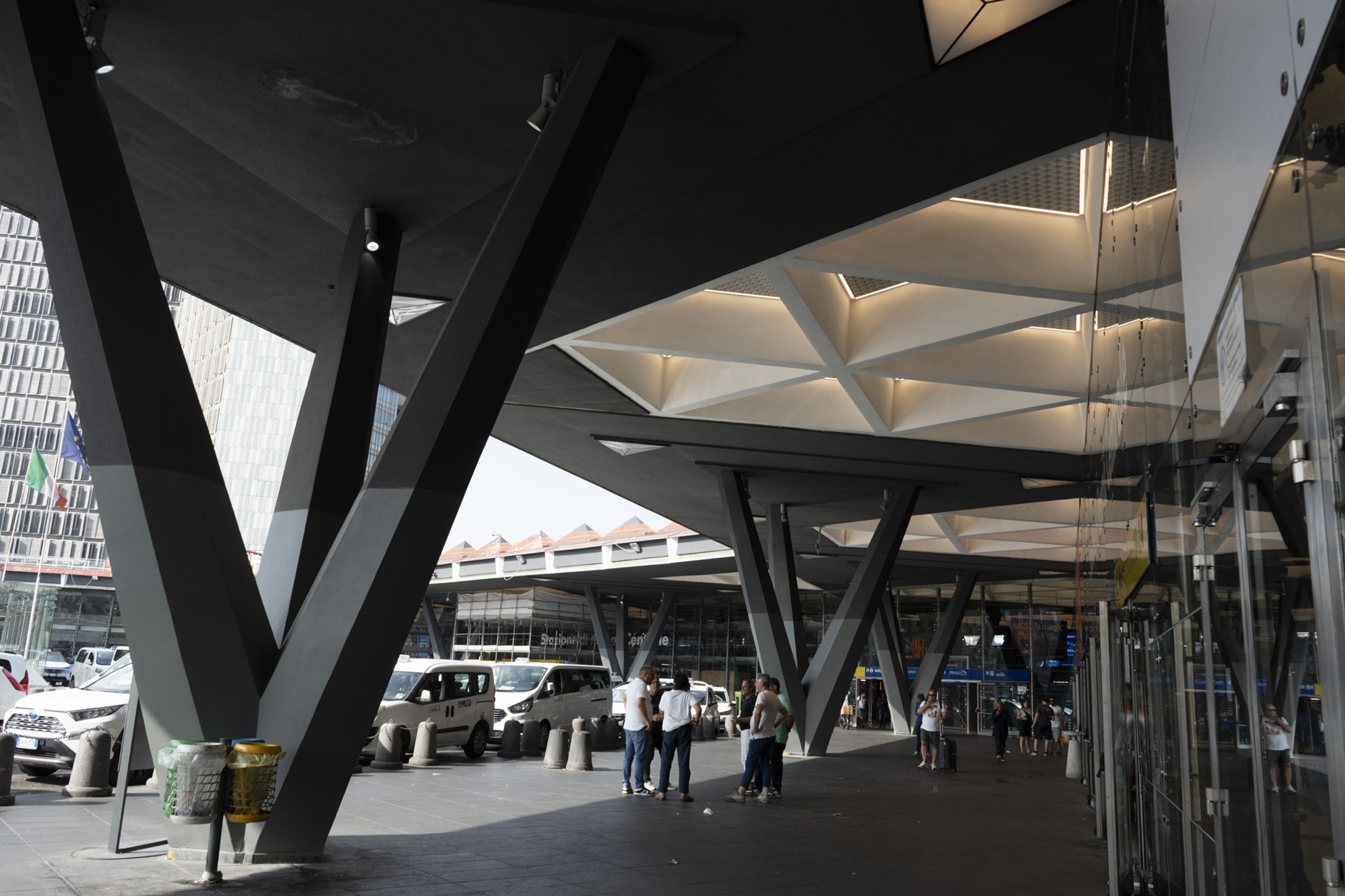 Una estructura arquitectónica moderna con diseño geométrico, con fachada de vidrio y una serie de vigas entrelazadas.