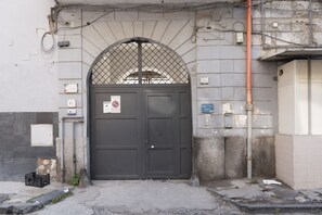 A closed dark door with a metal grid over the top, a sign prohibiting parking, and a small trash bin to the left. - Casa Cidis by Wonderful Italy (Naples)