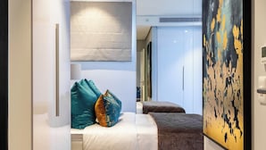 Un dormitorio moderno con cama, almohadas y un cuadro abstracto grande.