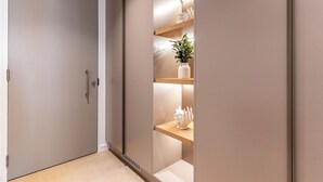 A modern hallway with a closed door, a plant on a shelf, and a decorative item on a lower shelf. - Stunning Green Point Apartment (Cape Town)