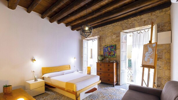 A bedroom with a wooden bed, a nightstand, a dresser, and a painting on the wall.