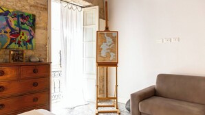 A room with a wooden dresser, a beige sofa, a colorful abstract painting, and a map on a wooden easel.