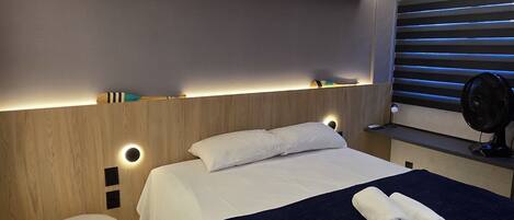 A modern bedroom with a bed, bedside table, and a small stool.