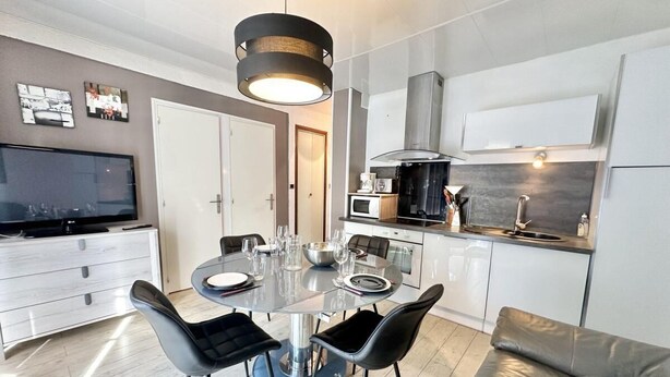 Une cuisine moderne avec une table de salle à manger ronde, des chaises noires et un four encastré.