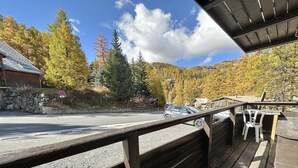 Une terrasse en bois dotée d’une rambarde, qui offre une vue sur une route et sur une chaîne de montagnes en arrière-plan.