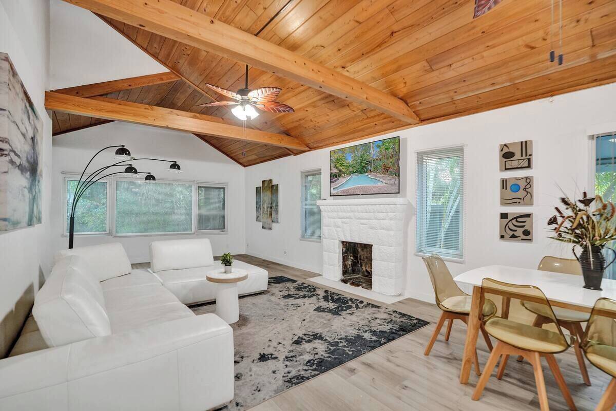 A spacious living area with a white fireplace, a ceiling fan, and a dining area with a white table and chairs.