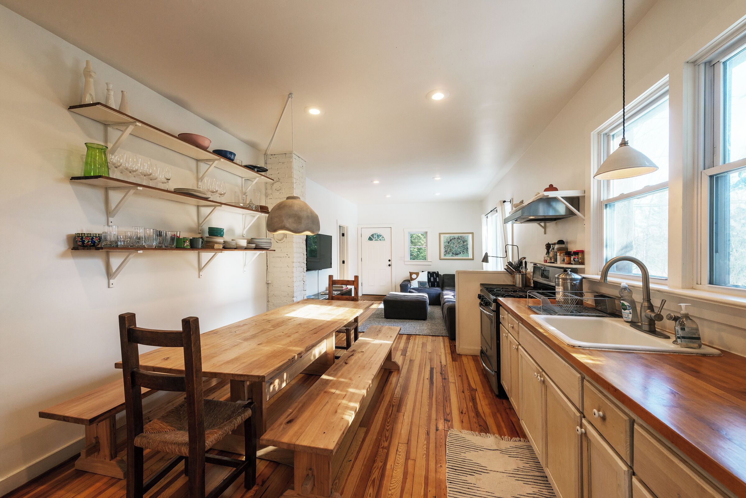 A modern kitchen with wooden flooring, a dining table, and built-in shelves.