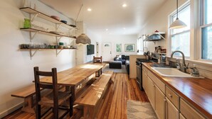 A modern kitchen with wooden flooring, a dining table, and built-in shelves.