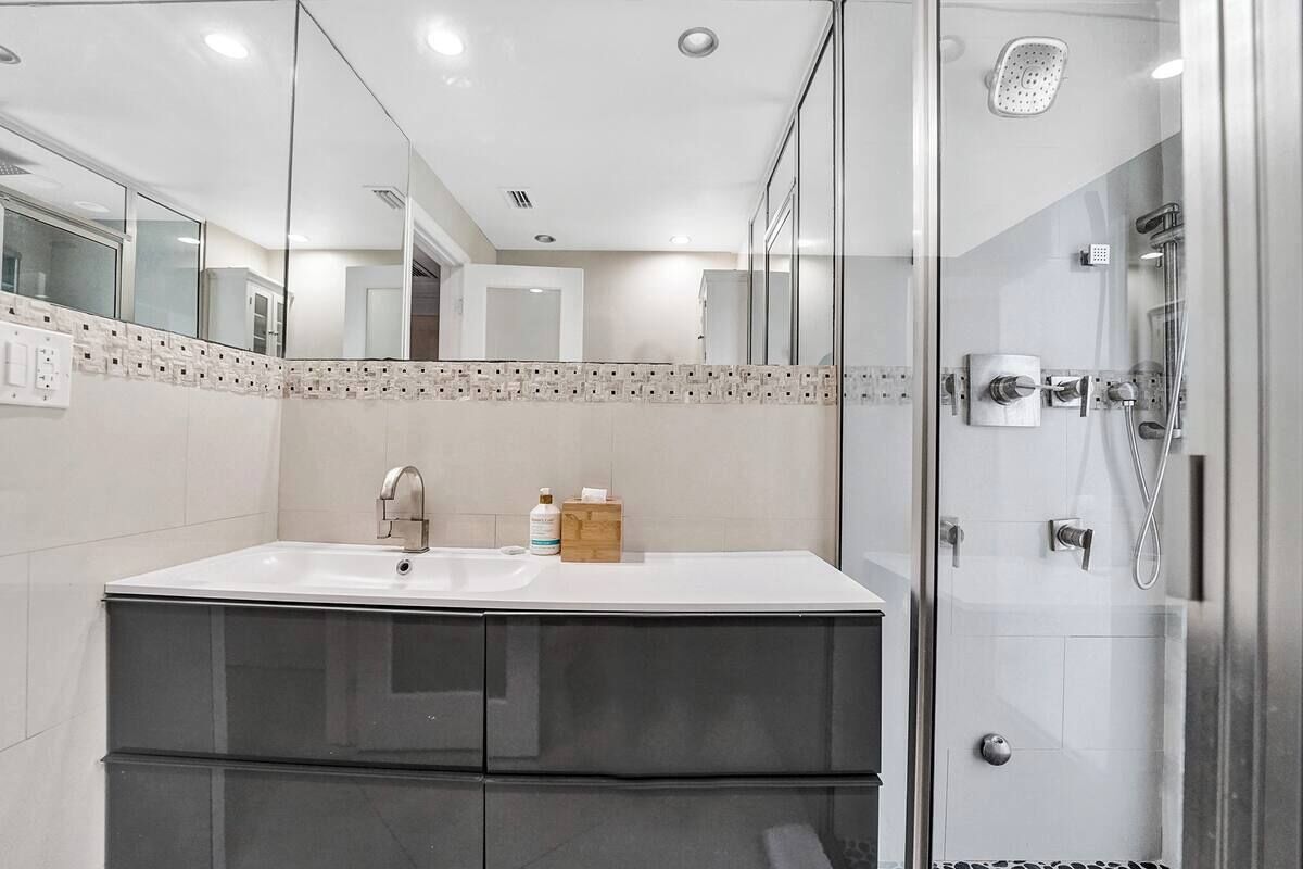 A modern bathroom with a double sink, a glass shower enclosure, and a mirrored wall.