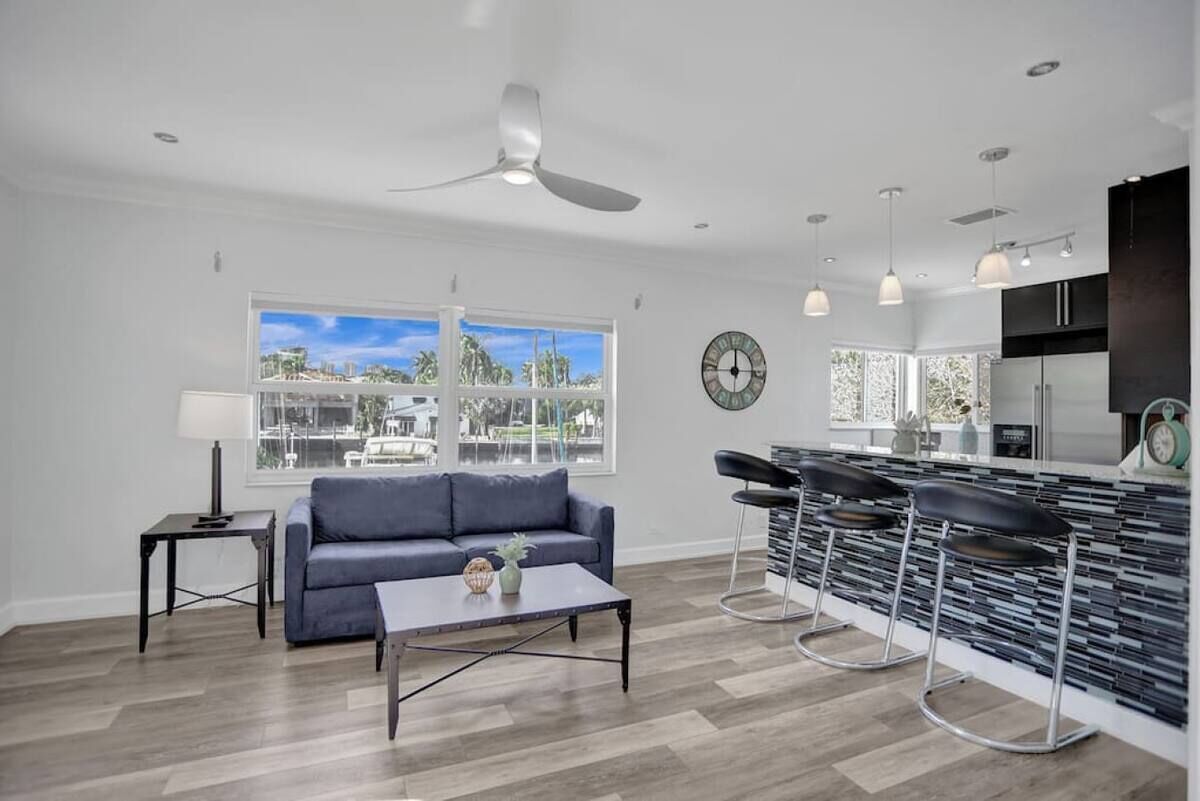 A modern living room with a sofa, coffee table, and a view of the city through large windows.