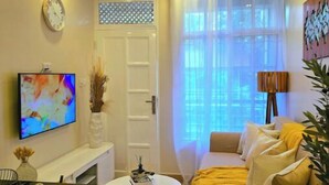 Un salon moderne avec un canapé, une table basse, un téléviseur et un ventilateur de plafond.