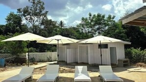 Un espace piscine agrémenté de chaises longues et de parasols, entouré d’une terrasse en briques et d’une plateforme en bois.