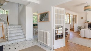 A spacious living area with a staircase, a dining table, and a sofa.