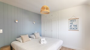 A bedroom with a bed, a hanging light fixture, a wall-mounted sign, and a wardrobe.