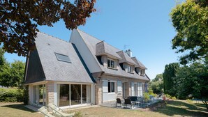 A house with a sloped roof, a covered patio with outdoor furniture, and a well-maintained lawn.