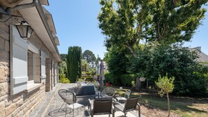 A patio with stone flooring, outdoor furniture, and a small tree.