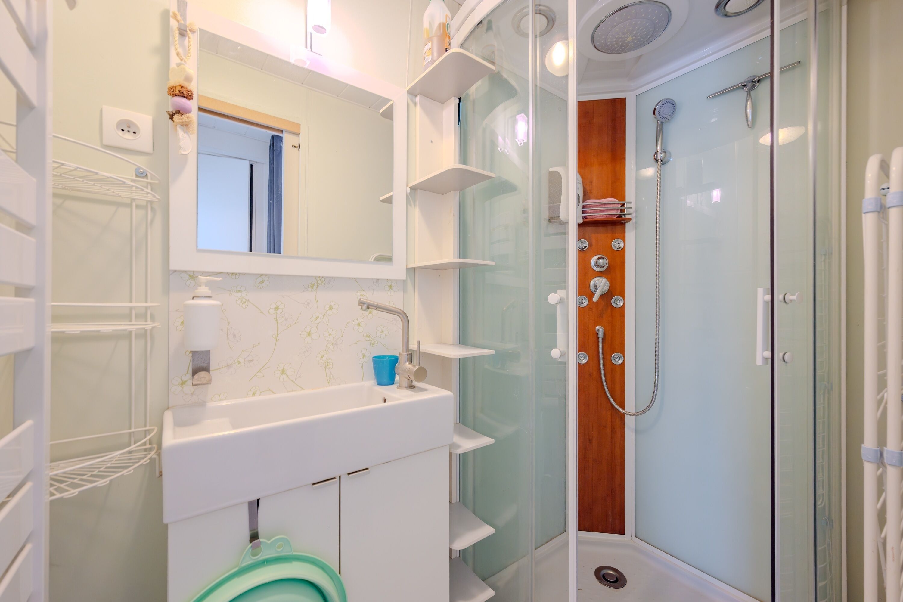 Een moderne badkamer met een witte wastafel, spiegel en douchecabine met glazen wanden.