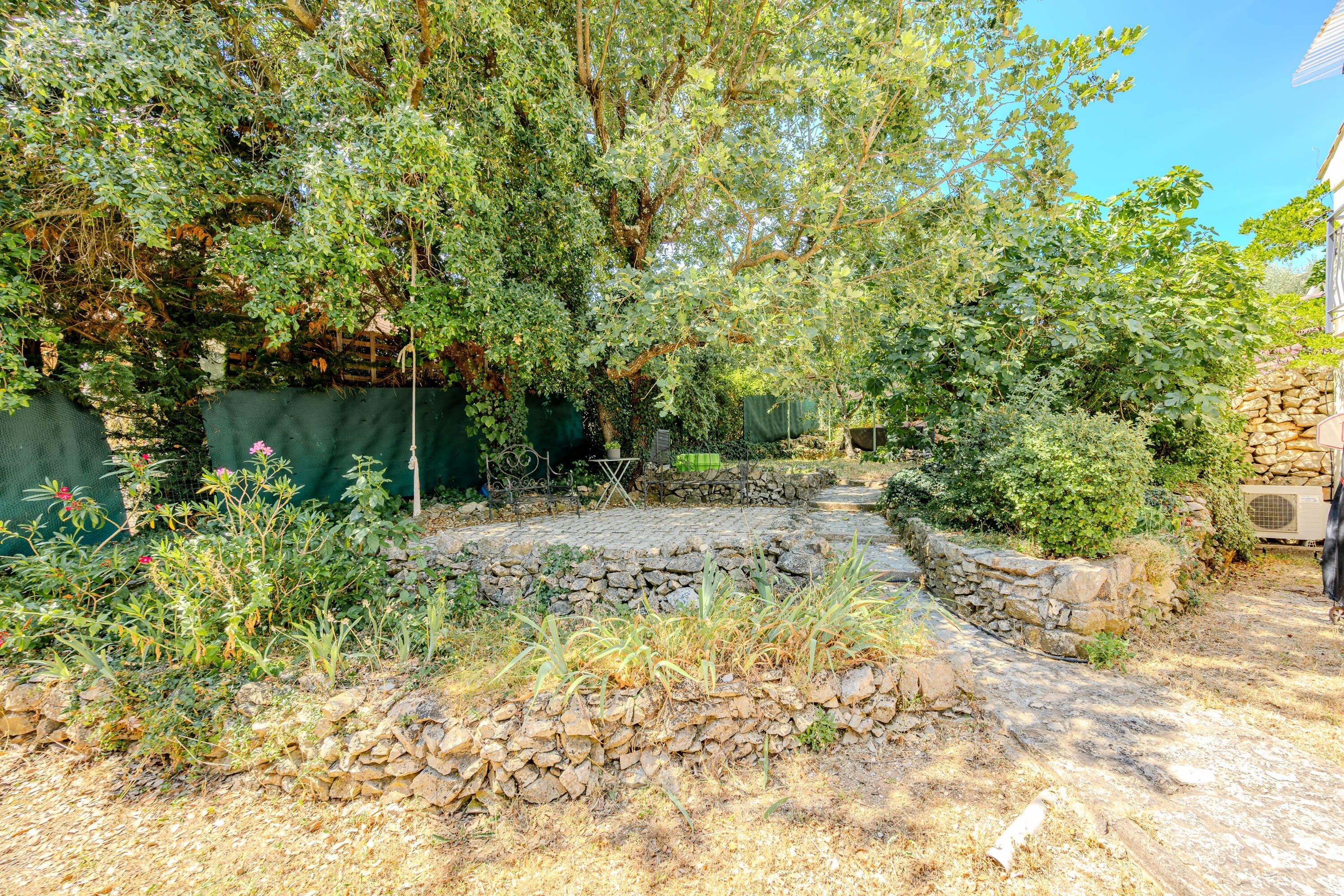 A garden with a stone pathway, a wooden fence, and a stone wall.