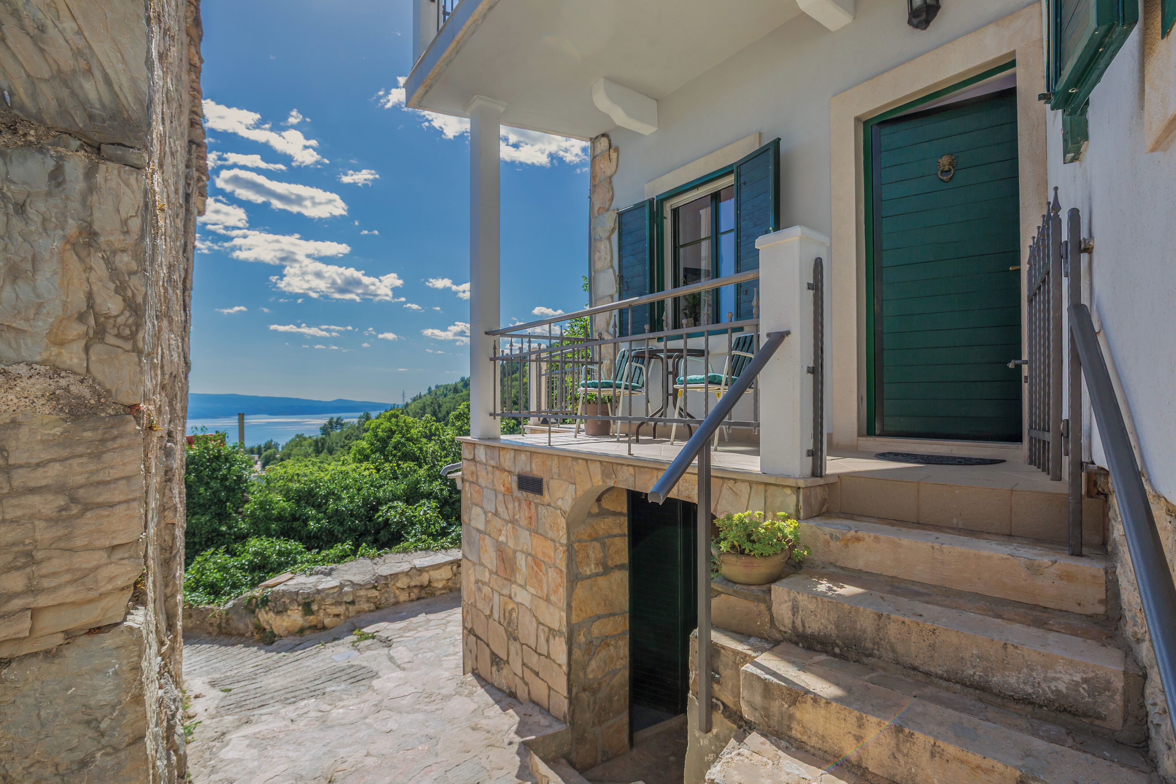 A stone staircase leading to a balcony with a view of the sea.